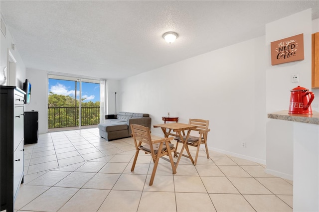 dining area with expansive windows, light tile patterned floors, and a textured ceiling