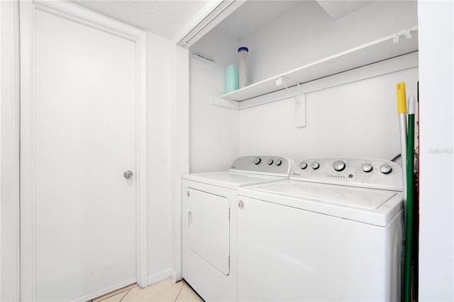 laundry area featuring washer and clothes dryer, light tile patterned floors, and a textured ceiling