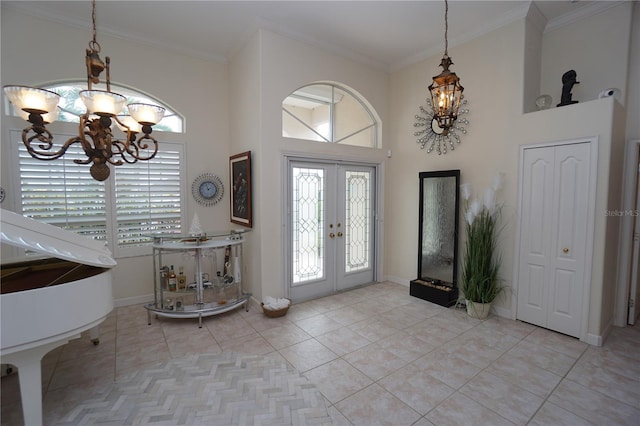 tiled entrance foyer with french doors, ornamental molding, a high ceiling, and an inviting chandelier