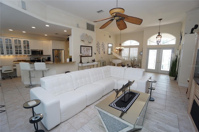 living room with french doors, light tile patterned floors, ceiling fan with notable chandelier, and ornamental molding