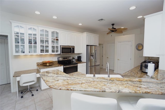 kitchen featuring white cabinets, appliances with stainless steel finishes, kitchen peninsula, and light stone counters