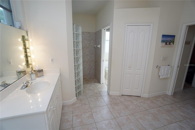 bathroom with tile patterned flooring, vanity, and a tile shower