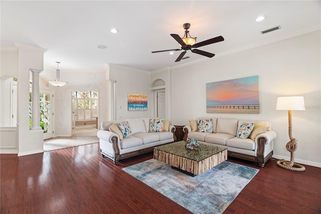 living room featuring ceiling fan, ornamental molding, dark wood-type flooring, and decorative columns