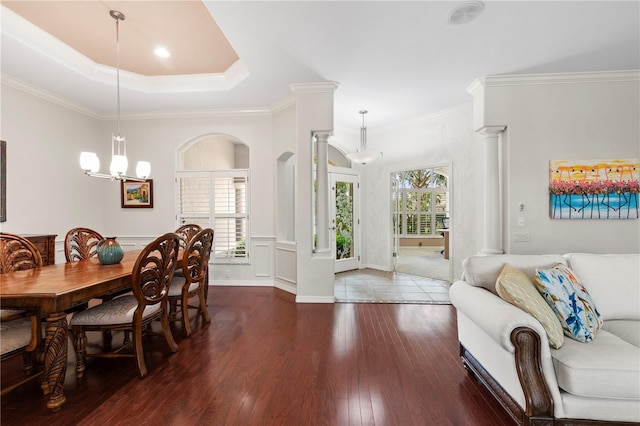 dining room featuring dark hardwood / wood-style floors, an inviting chandelier, decorative columns, and crown molding