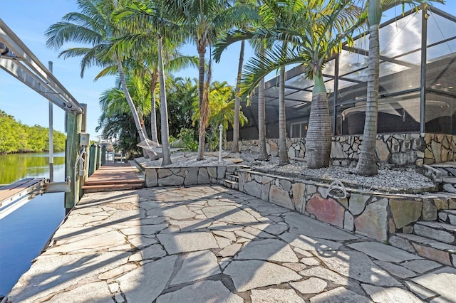 view of patio featuring glass enclosure and a water view