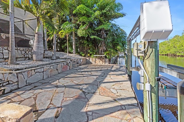 view of patio with a boat dock, a water view, and a lanai