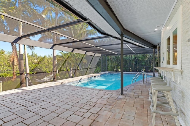 view of swimming pool with a patio, a water view, and glass enclosure