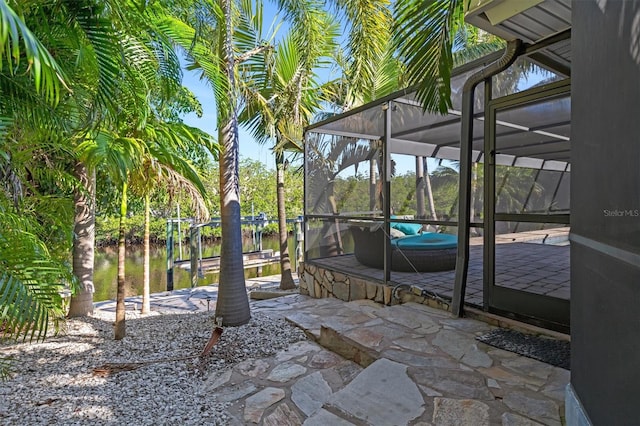 view of patio with glass enclosure and a water view