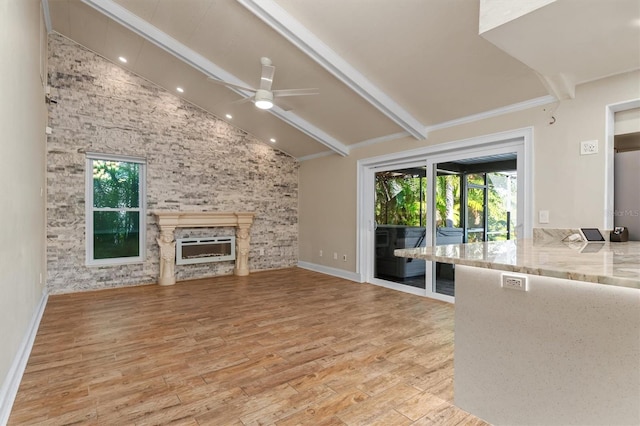 unfurnished living room featuring a fireplace, vaulted ceiling with beams, light wood-type flooring, and ceiling fan