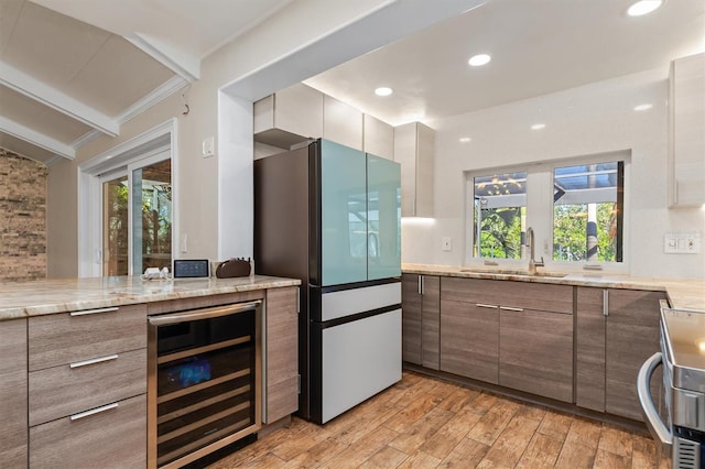 kitchen featuring sink, a healthy amount of sunlight, stainless steel appliances, wine cooler, and light hardwood / wood-style floors