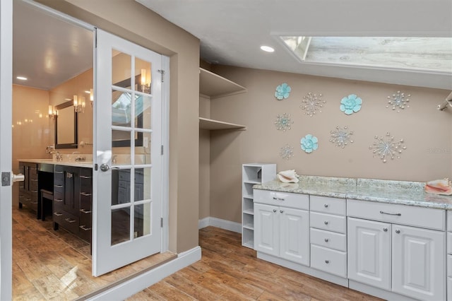 interior space with a skylight, sink, and light hardwood / wood-style floors