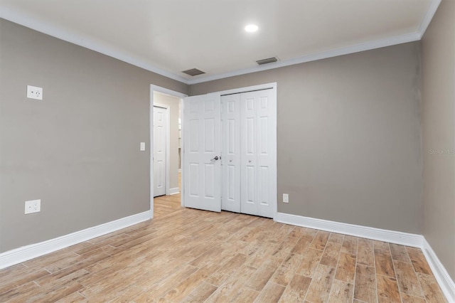 unfurnished bedroom featuring light wood-type flooring, ornamental molding, and a closet