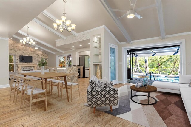 interior space featuring lofted ceiling with beams, crown molding, a fireplace, ceiling fan with notable chandelier, and light wood-type flooring