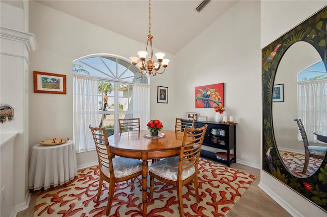 dining space with light hardwood / wood-style flooring, a healthy amount of sunlight, lofted ceiling, and an inviting chandelier