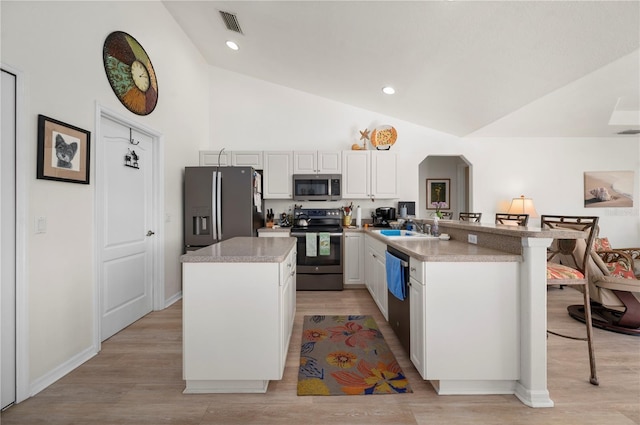 kitchen with a kitchen breakfast bar, light wood-type flooring, stainless steel appliances, sink, and white cabinets