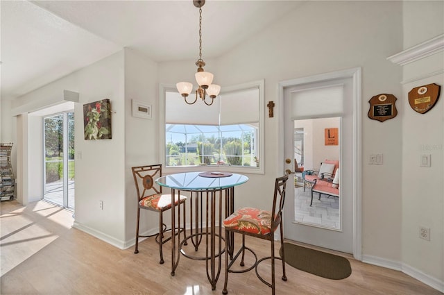 dining space featuring light hardwood / wood-style floors, vaulted ceiling, and a chandelier