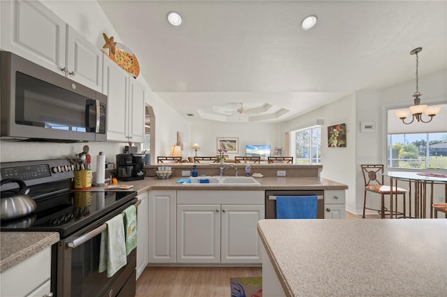 kitchen featuring appliances with stainless steel finishes, ceiling fan with notable chandelier, white cabinetry, and sink