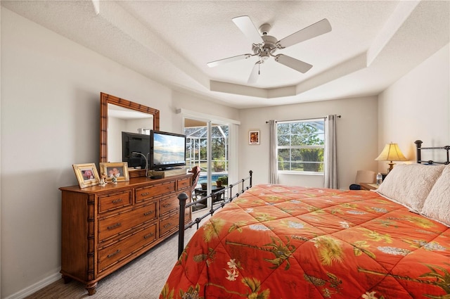 carpeted bedroom with a raised ceiling, ceiling fan, and a textured ceiling