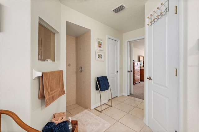 bathroom featuring a tile shower, tile patterned floors, and a textured ceiling