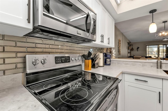 kitchen with hanging light fixtures, tasteful backsplash, a chandelier, white cabinets, and appliances with stainless steel finishes