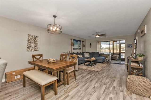 dining area featuring ceiling fan with notable chandelier and light hardwood / wood-style floors