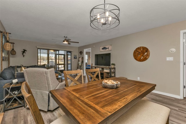 dining area with ceiling fan with notable chandelier, french doors, and light wood-type flooring