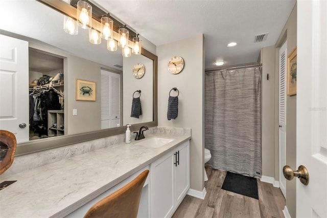 bathroom featuring hardwood / wood-style floors, vanity, toilet, and walk in shower