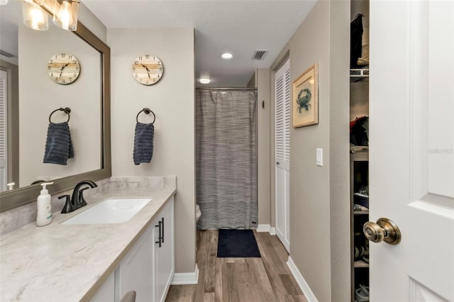 bathroom featuring hardwood / wood-style floors, vanity, toilet, and walk in shower