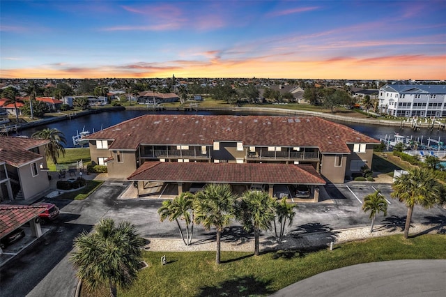 aerial view at dusk featuring a water view and a residential view