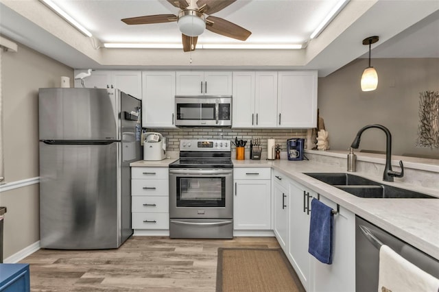 kitchen featuring a sink, light countertops, white cabinets, appliances with stainless steel finishes, and tasteful backsplash