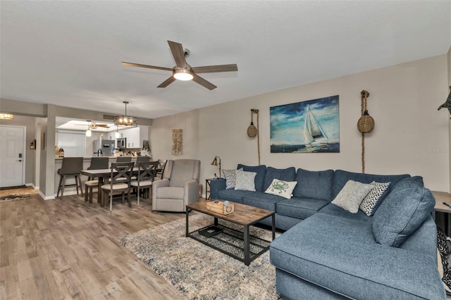 living area with baseboards, wood finished floors, and a ceiling fan