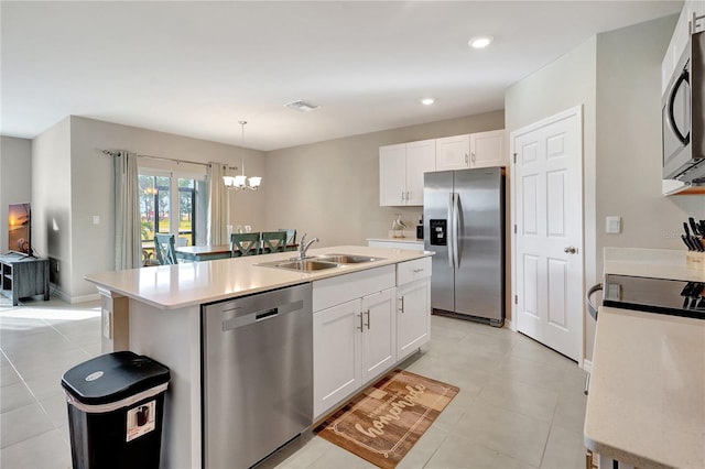 kitchen with white cabinets, sink, stainless steel appliances, and an island with sink