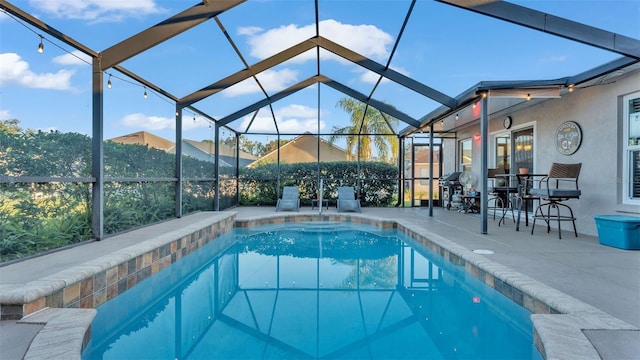 view of pool with glass enclosure and a patio