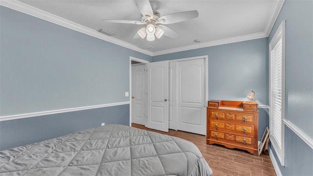 bedroom featuring ceiling fan, ornamental molding, light hardwood / wood-style flooring, and a closet