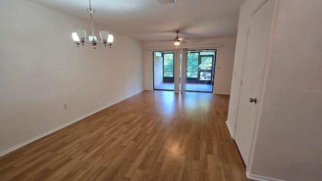 spare room featuring hardwood / wood-style floors and ceiling fan with notable chandelier