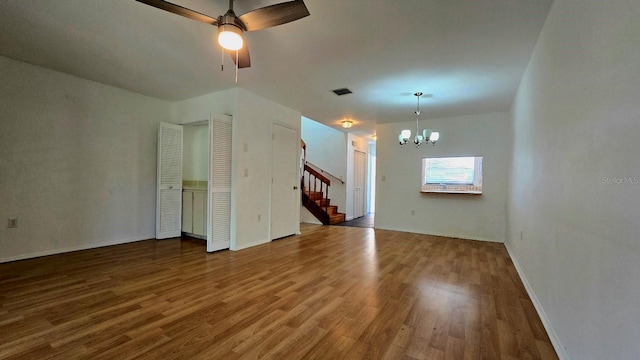 spare room featuring ceiling fan with notable chandelier and wood-type flooring