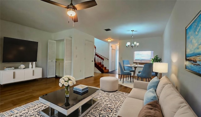 living room with ceiling fan with notable chandelier and dark wood-type flooring