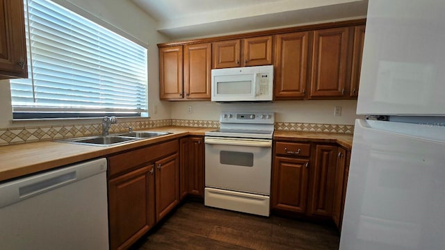 kitchen featuring dark hardwood / wood-style flooring, white appliances, and sink