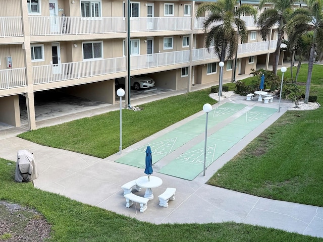 view of home's community featuring shuffleboard and a yard