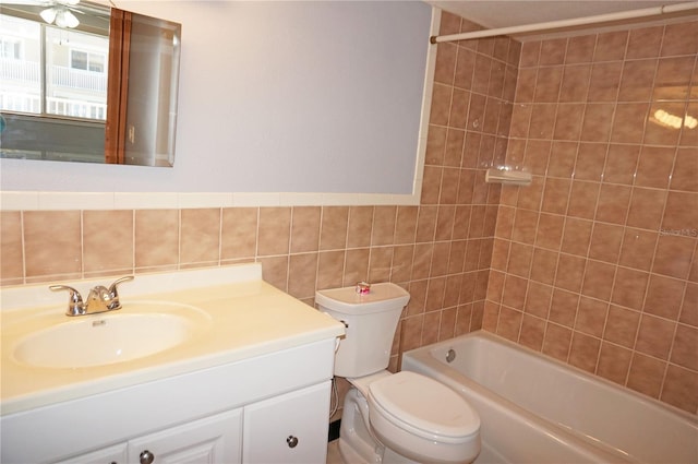 bathroom with toilet, bathtub / shower combination, vanity, and tile walls