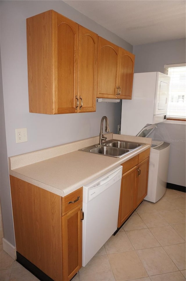 kitchen with washer / clothes dryer, light countertops, light tile patterned flooring, white dishwasher, and a sink