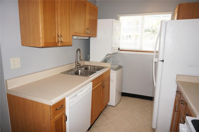 kitchen featuring light tile patterned flooring, white appliances, a sink, light countertops, and brown cabinetry