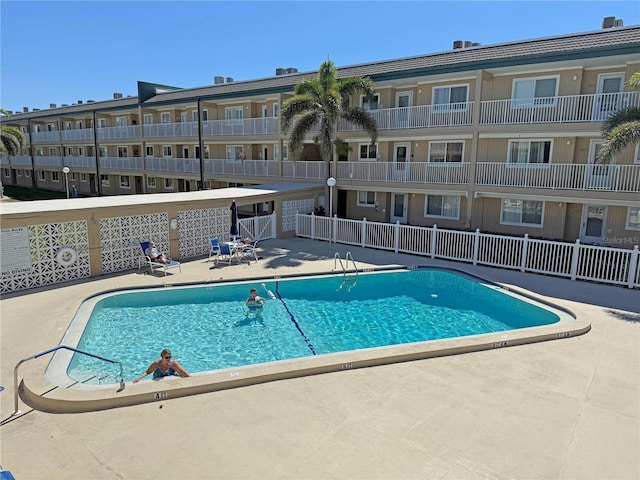 community pool with fence and a patio