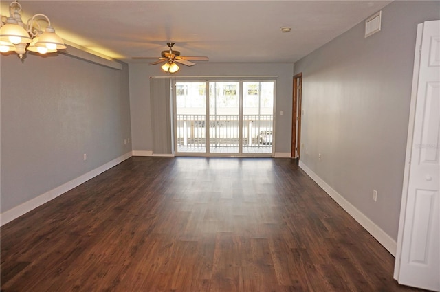 spare room with dark wood-style flooring, visible vents, baseboards, and ceiling fan with notable chandelier