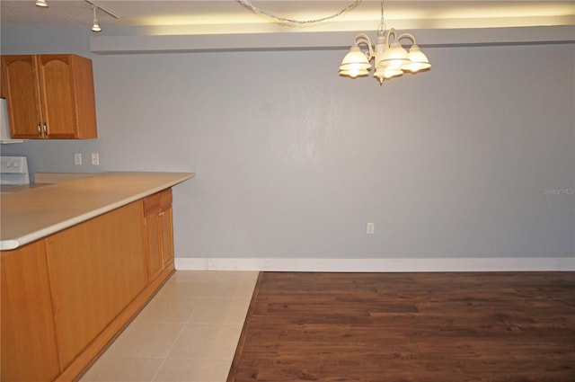 kitchen with baseboards, an inviting chandelier, light countertops, track lighting, and light tile patterned flooring