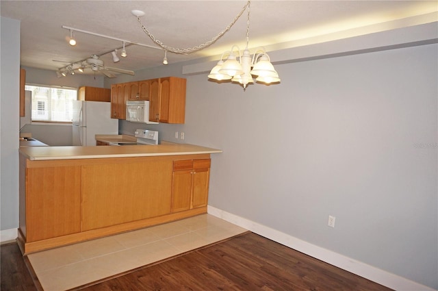 kitchen with white appliances, baseboards, wood finished floors, light countertops, and a notable chandelier