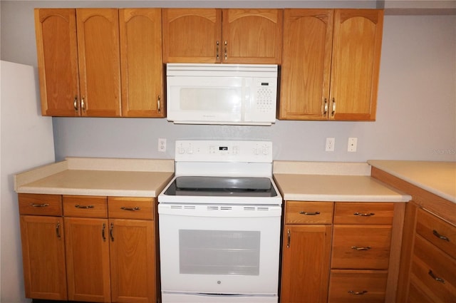 kitchen featuring light countertops, white appliances, and brown cabinetry