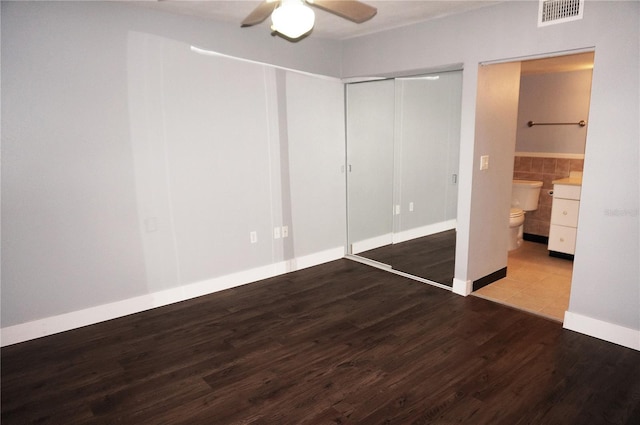 unfurnished bedroom with wood finished floors, visible vents, tile walls, a closet, and ensuite bath