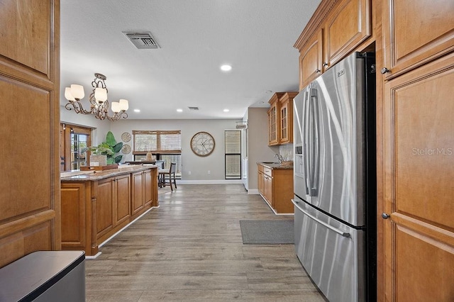 kitchen with pendant lighting, light hardwood / wood-style floors, stainless steel fridge with ice dispenser, and a chandelier