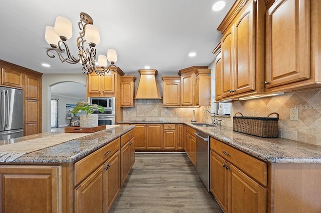 kitchen featuring sink, hanging light fixtures, a notable chandelier, a kitchen island, and stainless steel appliances